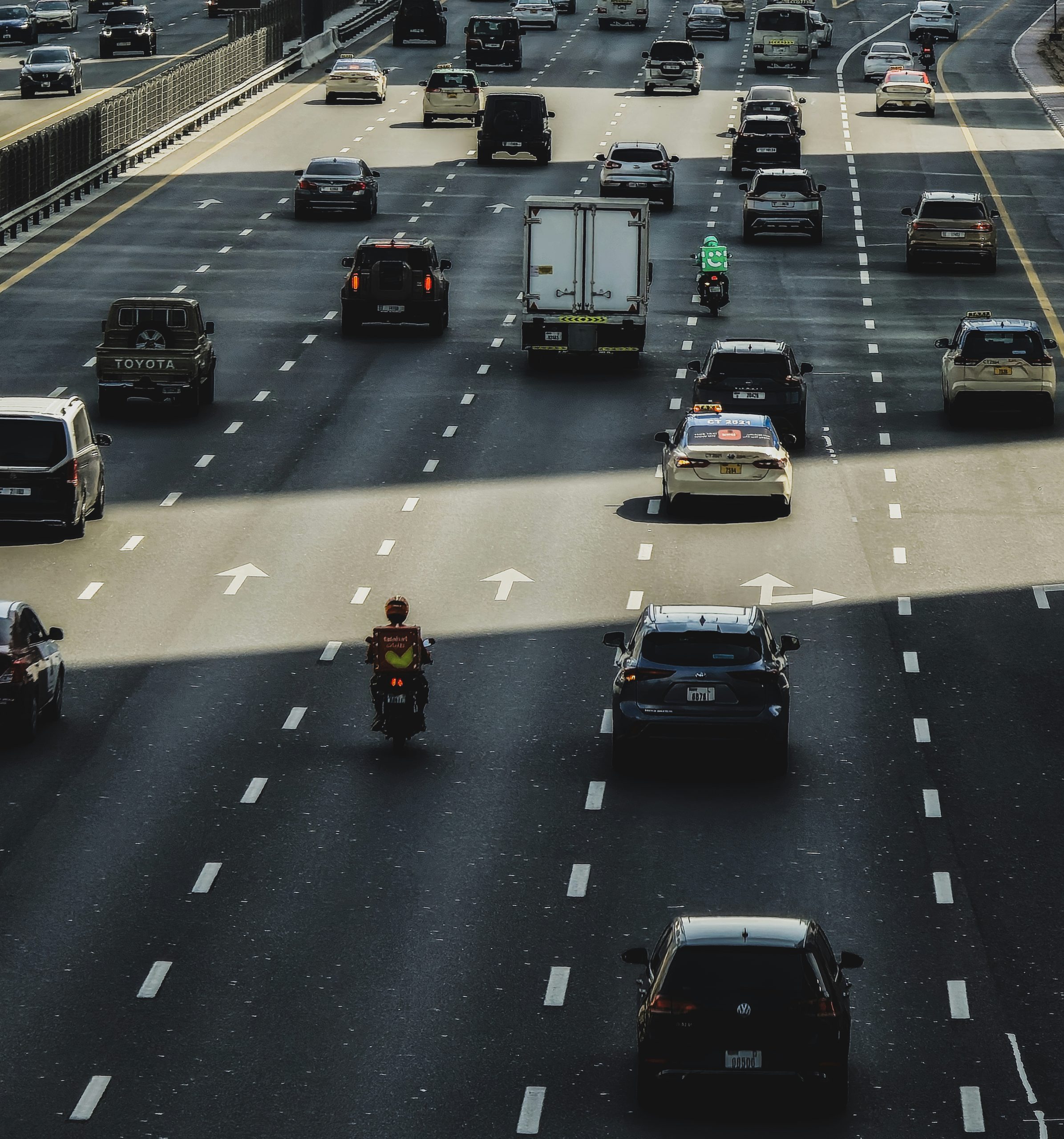 Busy multi-lane highway traffic with cars and delivery riders