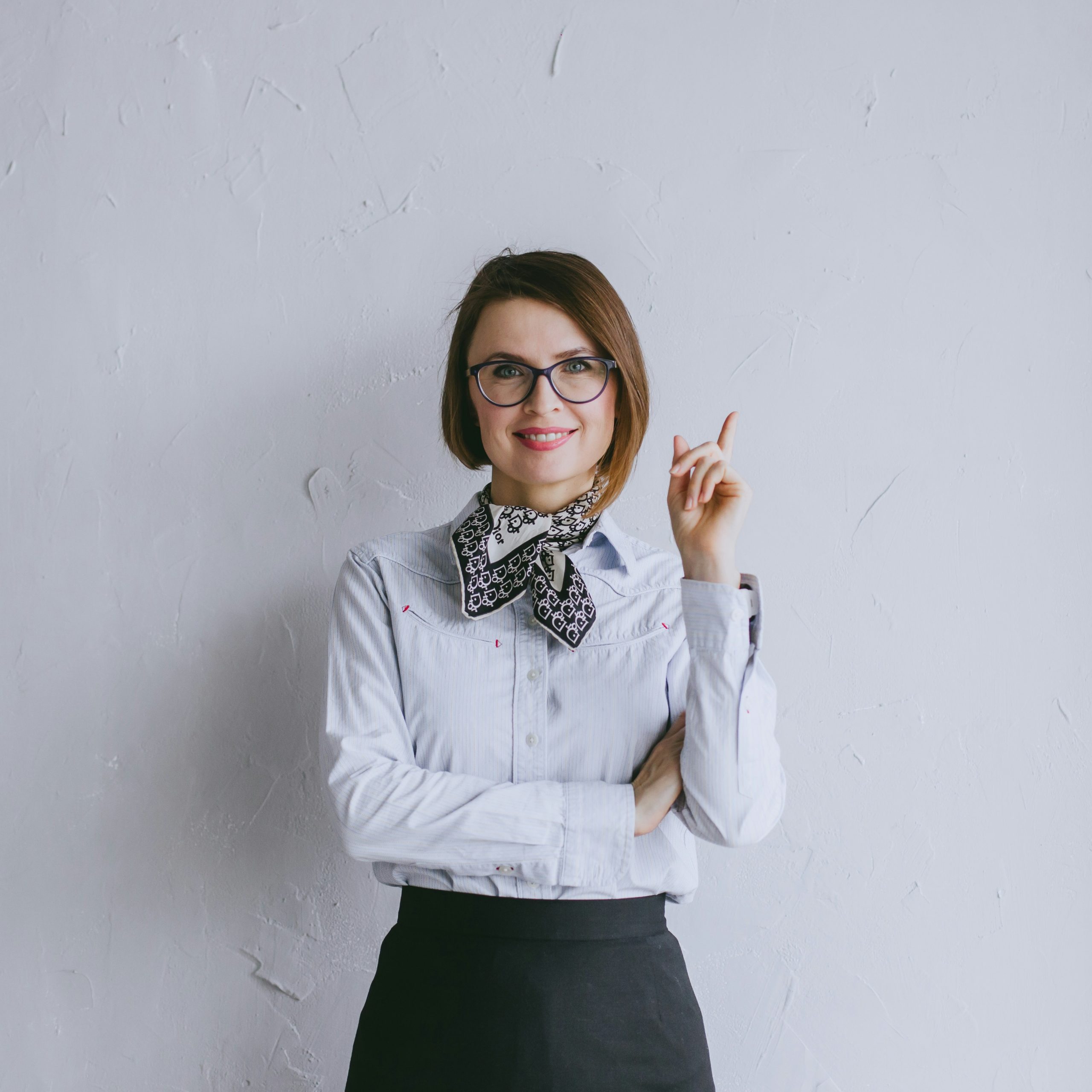 Smiling businesswoman in glasses pointing upward with an idea