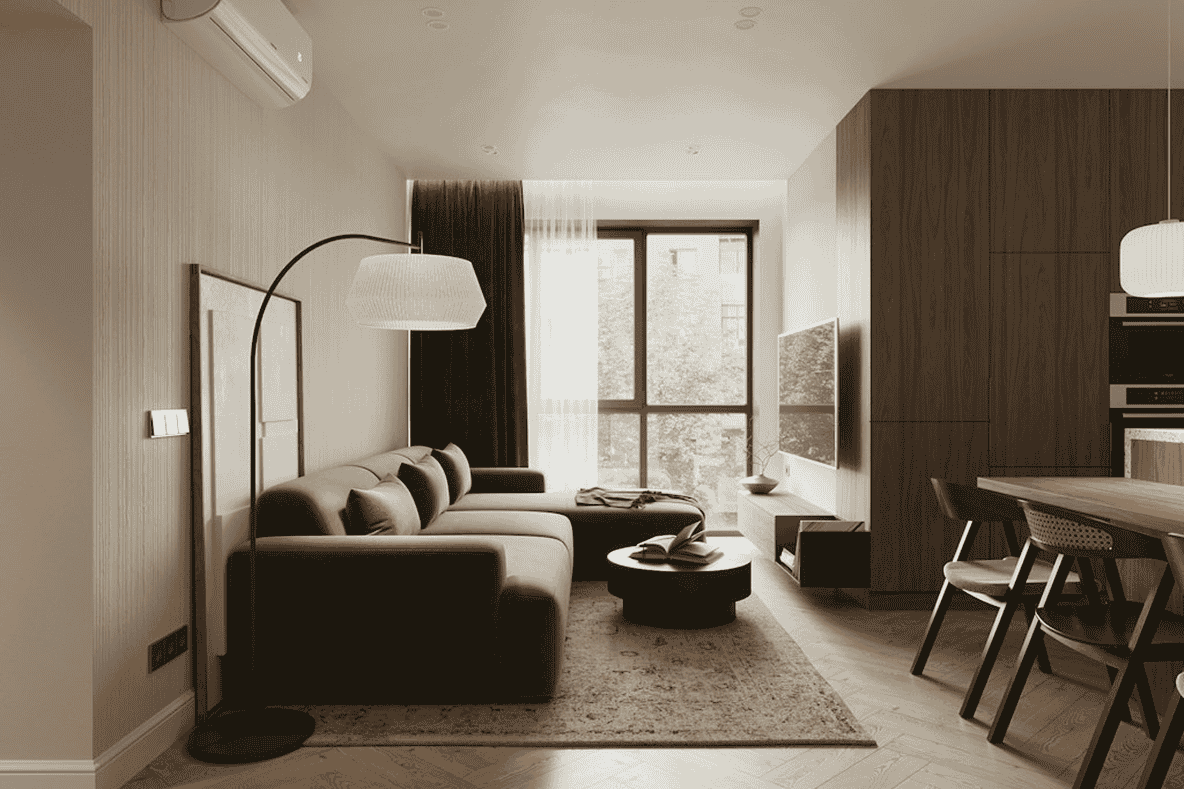 Modern open-plan living room and kitchen with a sofa, floor lamp, large window and wood cabinetry.