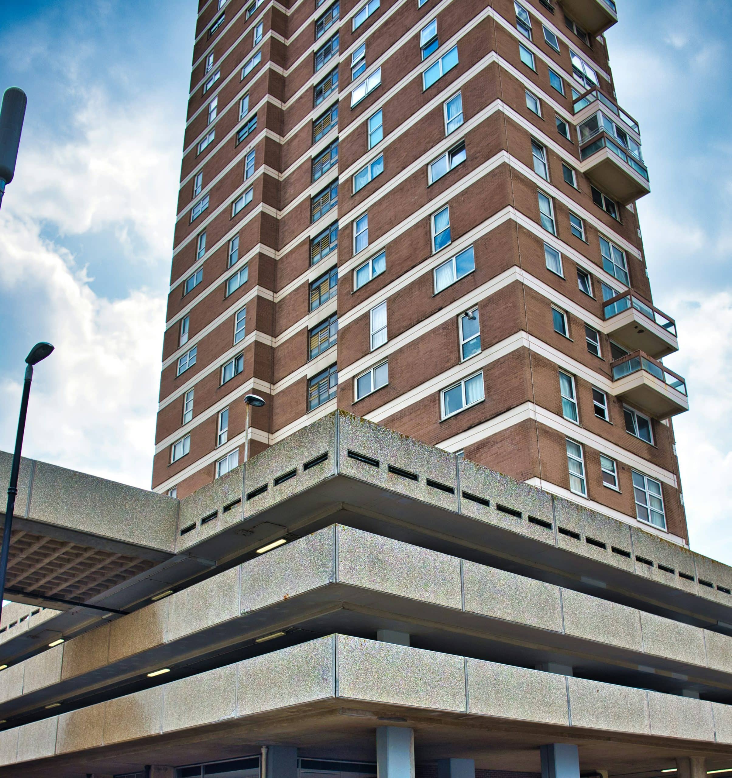 High-rise brick apartment tower above a concrete multi-storey car park